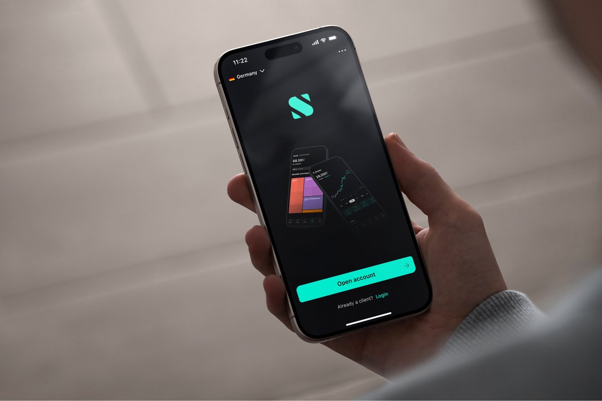 Hand hält ein Smartphone mit dem Startbildschirm der Scalable-Capital-App und dem S-Logo
